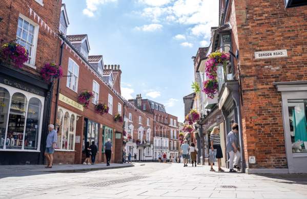 Lincoln's Bailgate street view with shopfronts and bunting on a sunny day with people shopping and walking along the pavement.