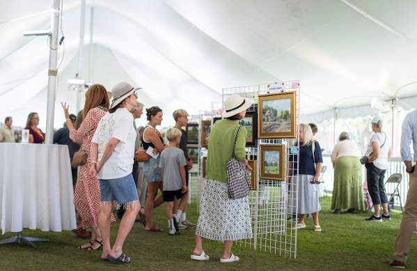 People looking at art in a tent during Paint Dexter Plain Aire