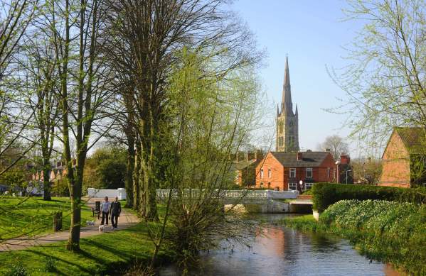 Man and woman walk their dog along the river side with church in background