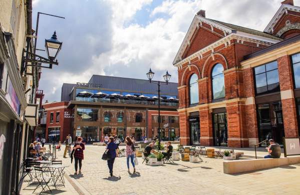 lively scene of Exchange Square in the Cornhill Quarter with people walking, shops in distance and clouds in the sky