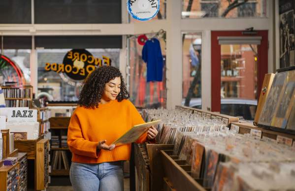 Encore Records- Woman in orange shirt looking at albums in a record store.