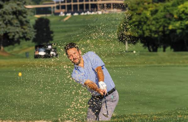 Man hitting golf shot out of sand