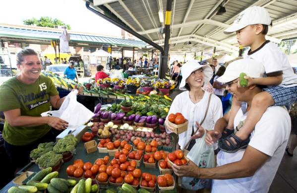 Family buying produce from a woman st the Ann Arbor Farmers Market