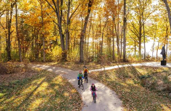 Family bikes on the B2B trail during fall on a dirt pathway with treelined background
