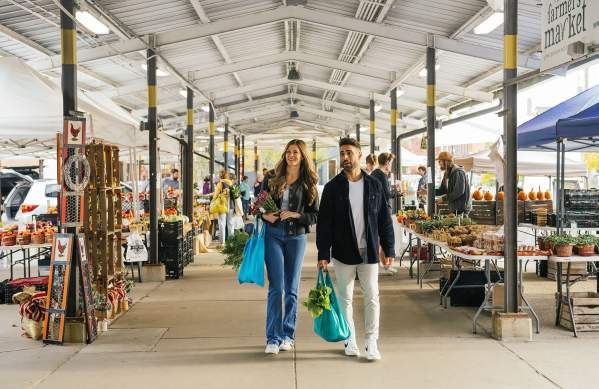Young couple with shopping totes walking through the Ann Arbor Farmers Market