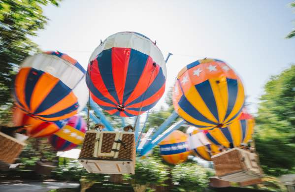 A Theme park ride consisting of imitation hot air balloons spinning in a circle with riders in the hanging baskets below.