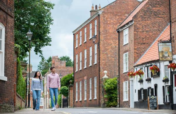 Two people walking along the street in Louth with a traditional country pub in the background