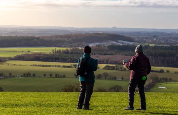 two people stood on a hill with rolling fields in background