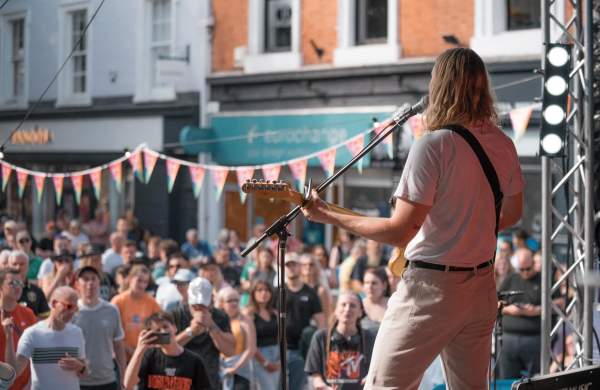 A live concert in Lincoln's Cornhill Quarter, a guitarist looks out over a crowd of people