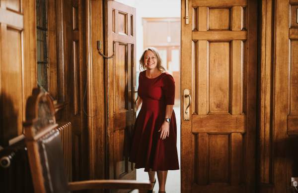 a woman in a red dress entering through large old wooden doors