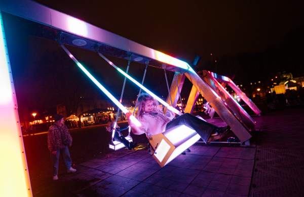 A young girl on a light up swing in the dark