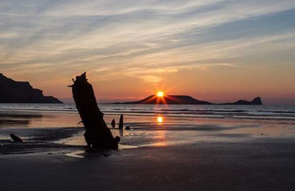 view of the helvetia shipwreck in rhossili against the sunset