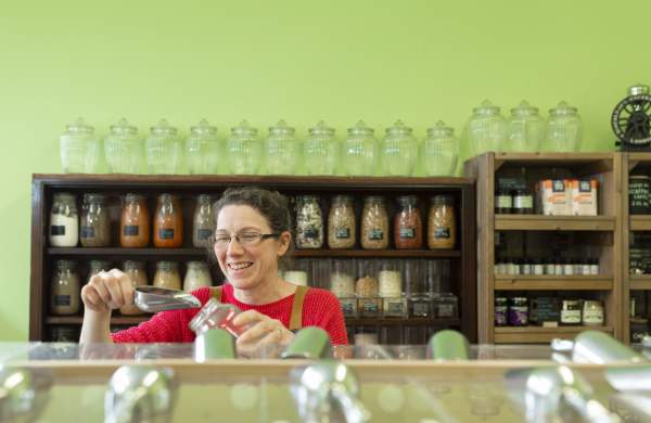 a woman pouring grain into a jar in a produce shop