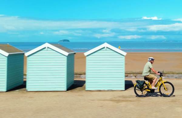 Cycling past beach huts in Weston-super-Mare - credit Siddiqui Media