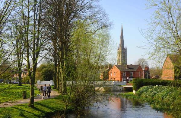 Man and woman walk their dog along the river side with church in background