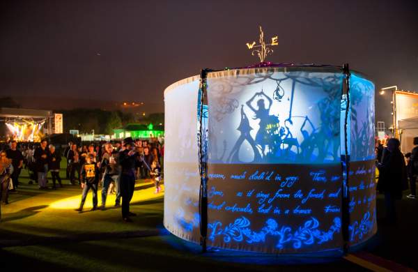 A light installation presenting a shadow puppet show with people watching