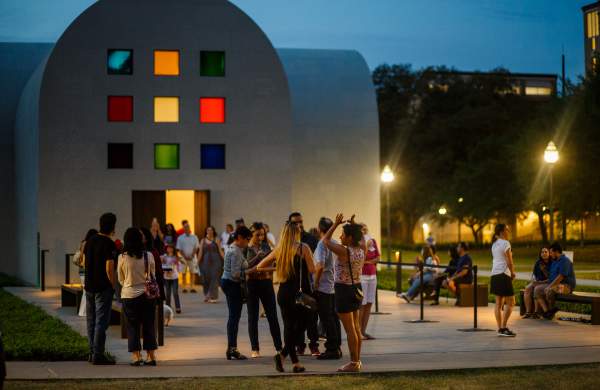 Groups of people gathering outside of Austin at the Blanton Museum at night.