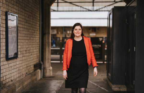 A woman in a red jacket walking through Lincoln train station