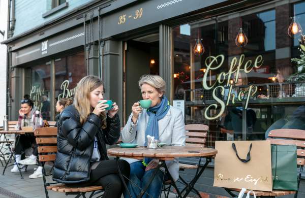 A mother and daughter enjoying coffee outside a cafe.
