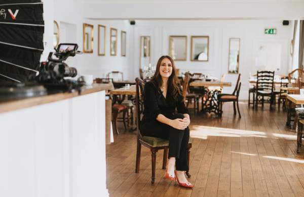 a woman sat on a chair in the centre of a restaurant space with cameras in the foreground