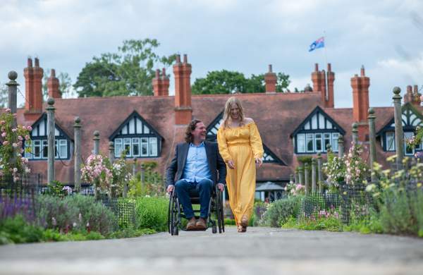 A man in a wheelchair and a woman laughing together on a path outside of Petwood Hotel