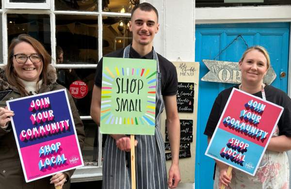 three people holding signs encouraging shoppers to shop small
