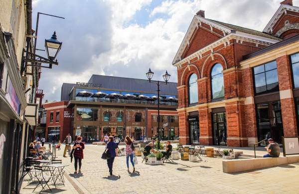 lively scene of Exchange Square in the Cornhill Quarter with people walking, shops in distance and clouds in the sky