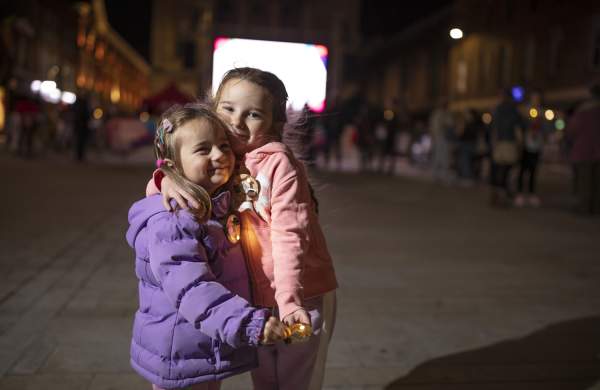 Two children embracing near a light installation