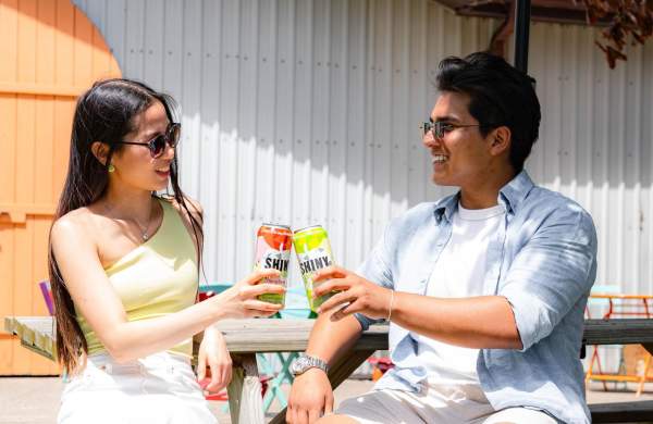 Couple drinking ciders on a picnic bench