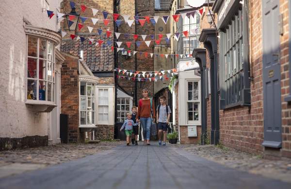 a family walking along a side street with bunting hanging from the buildings