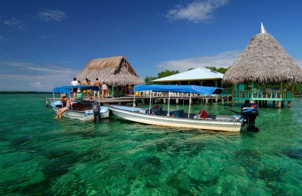 Turistas no píer da Isla Bastimentos embarcando em lanchas nas águas cristalinas do Parque Nacional Marinho Isla Bastimentos, em Bocas del Toro.