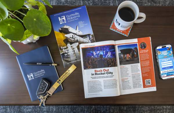 coffee table with an open book, a cup of coffee, a plant, an iphone, a journal and some car keys