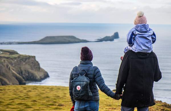A man and a woman looking out at Worm's head. The man has a child on his shoulder.