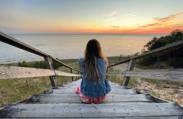 Woman sits on the dune staircase at Laketown Beach