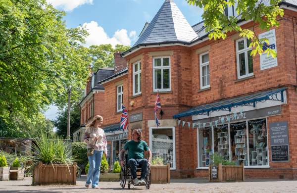 A woman walking down the street with a man in a wheelchair