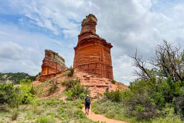 Man walking up to the beautiful red sandstone lighthouse rock structure (hoodoo) on a sunny day