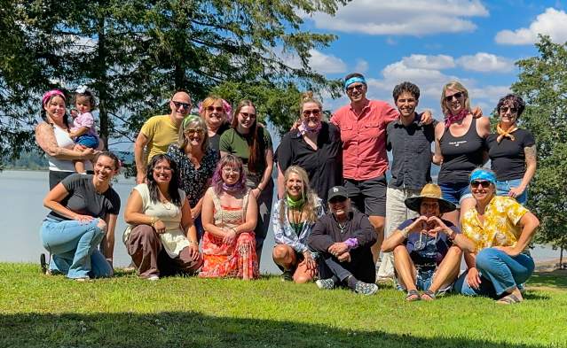 A portion of the staff for Travel Lane County on the grass by Fern Ridge during a team retreat.