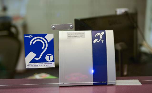 A hearing loop sign and device sits on a reception desk