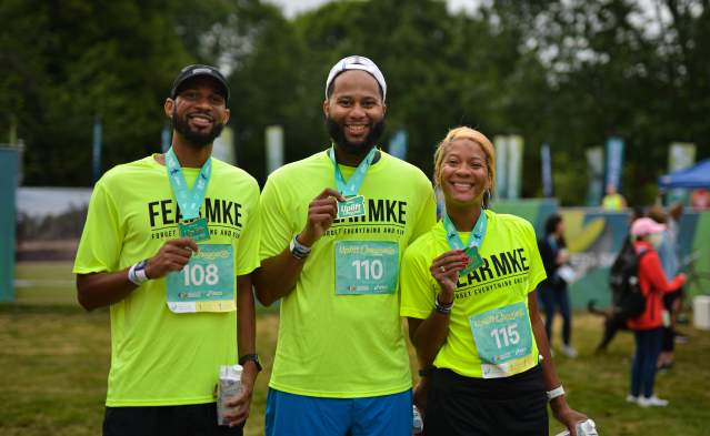Three people smile and show off their 5k medals during the World Championships Oregon22