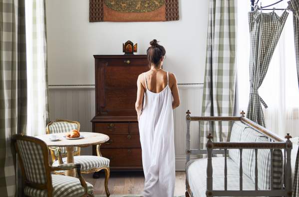 A woman in a white dress moves through a guest room at the upscale New Orleans boutique hotel Hotel Peter and Paul in the Marigny.