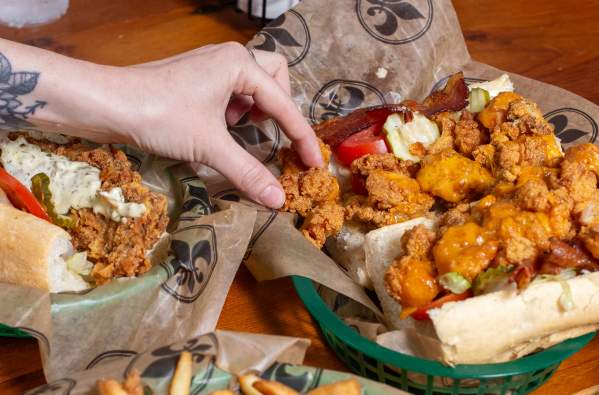 a person reaches for a fried shrimp po-boy and and french fries at Mahony's in New Orleans