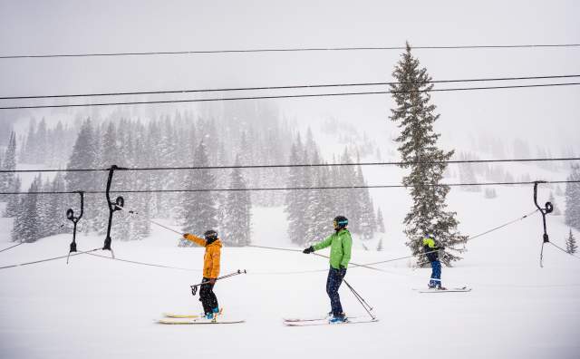 Two skiers on Alta's rope tow with chairlift lines in the background