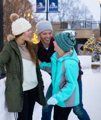 A white man looks at two young white girls while ice skating at The Edgewater