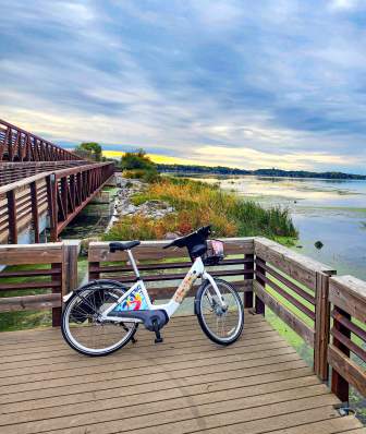A BCycle electric bike rests on a foot bridge overseeing the lake