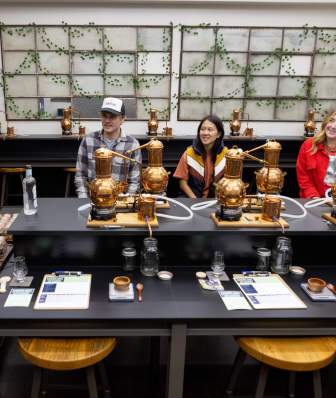 A white man leads a class of three people in making gin at Dancing Goat Distillery