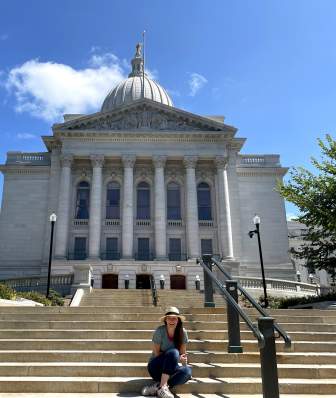 A woman sits in front of the Wisconsin State Capitol