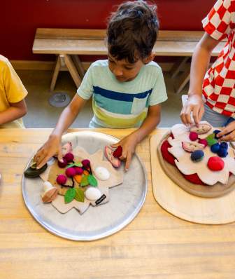 An overhead image of three kids making pizzas out of play toy food at the Madison Children's Museum.