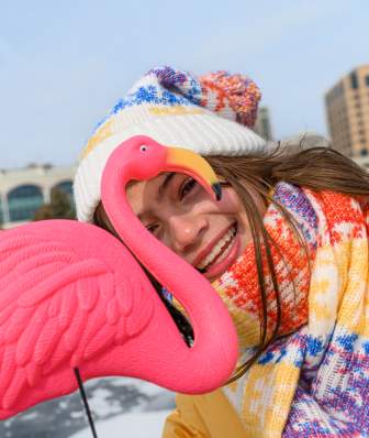 A young girl peaks through a plastic pink flamingo while standing on a frozen Lake Monona.