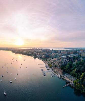A wide drone image of the city at sunset with Lake Mendota in the foreground