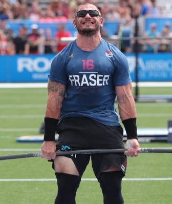 A CrossFit competitor lifts a dumbbell full of weight plates